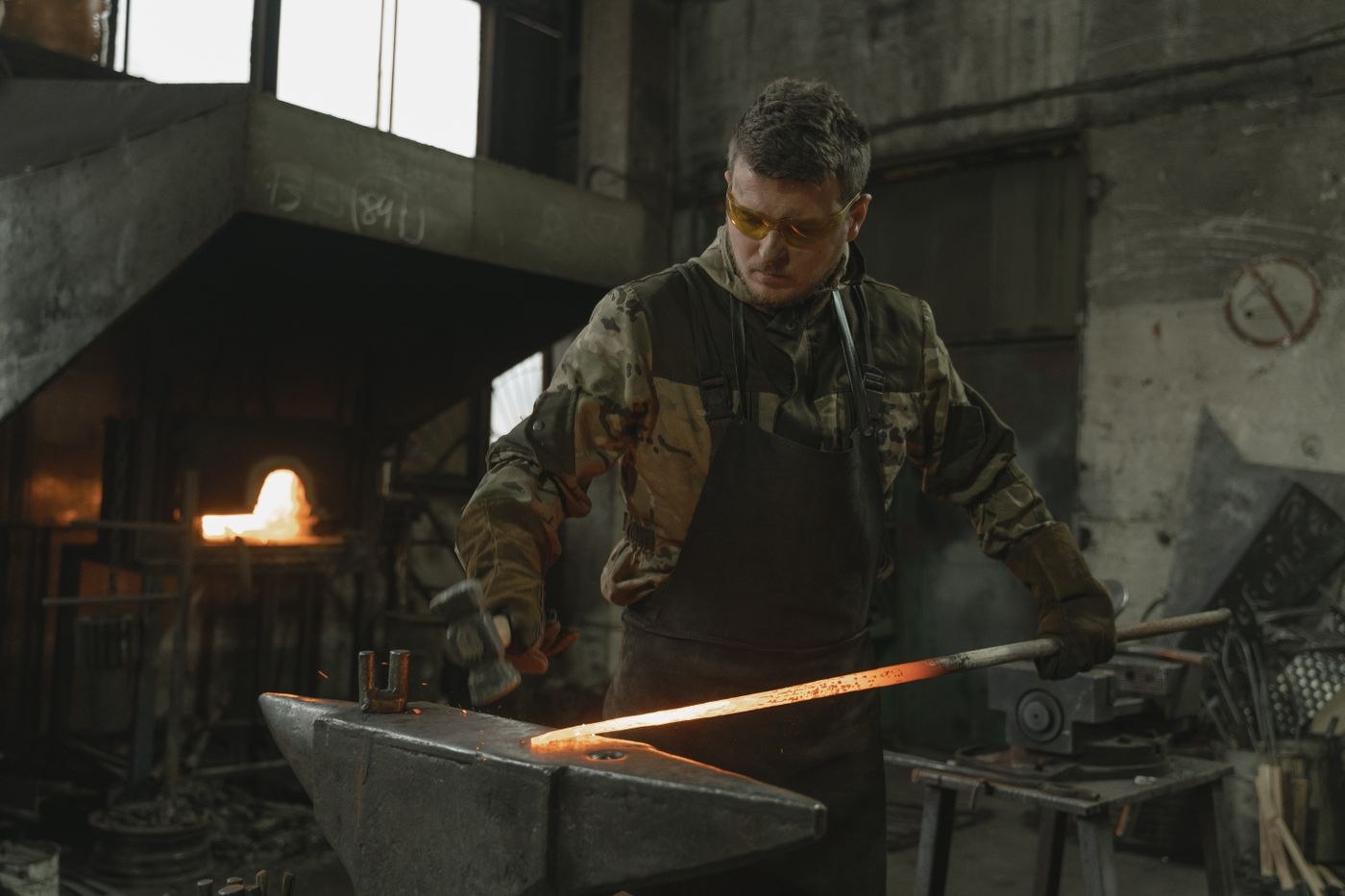 Blacksmith forging hot metal on an anvil in a forge