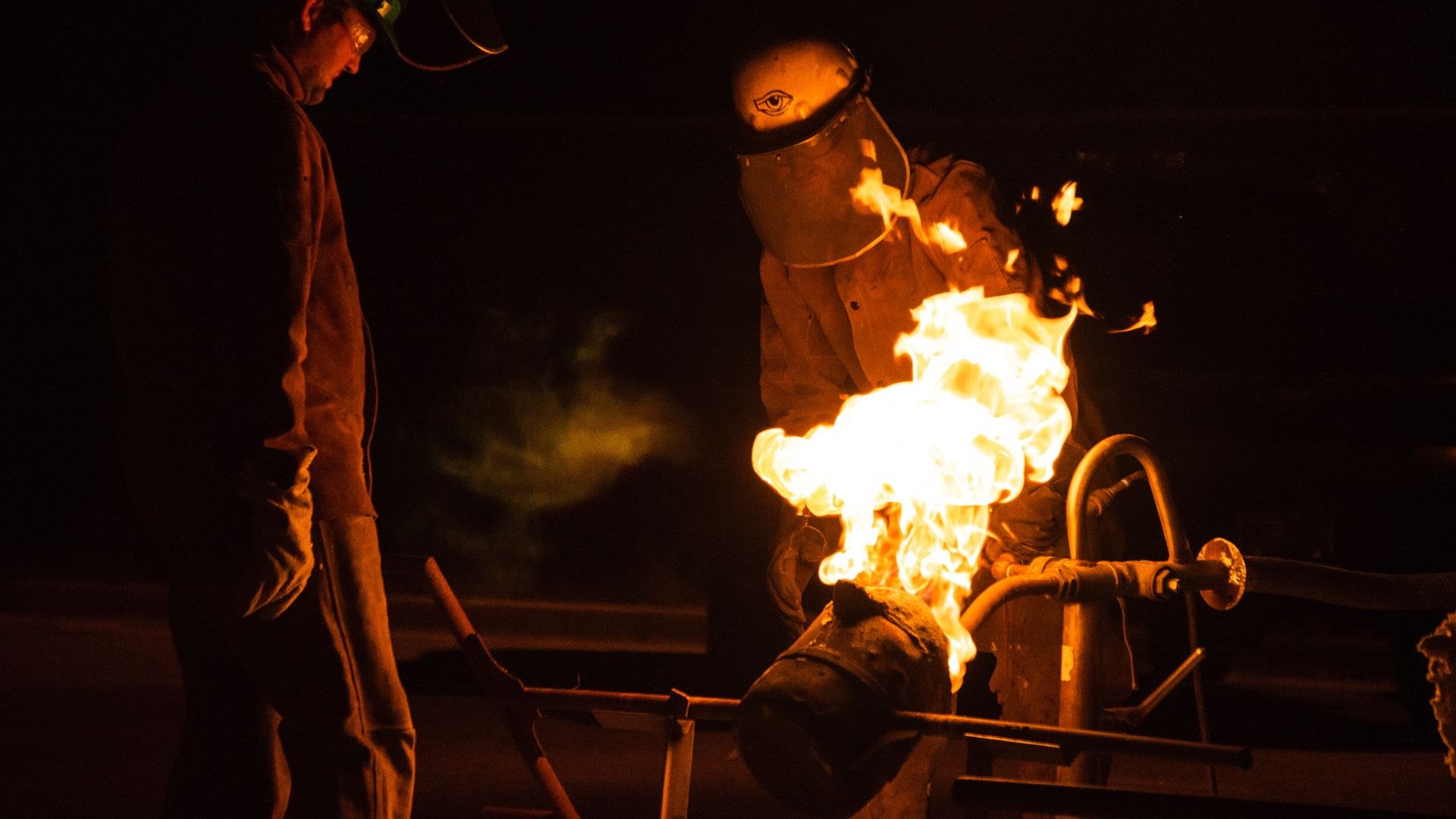 Foundry workers pouring molten metal in an industrial foundry, sparks flying